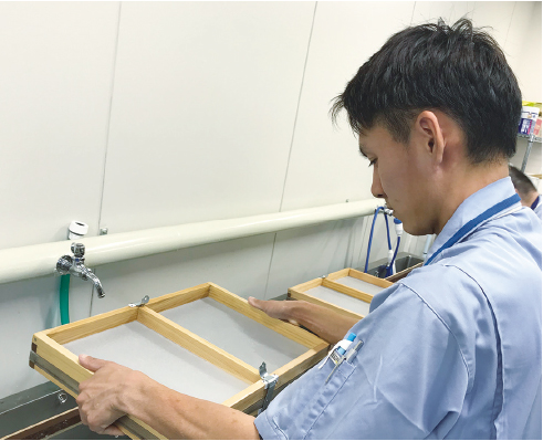 木枠に入った余分な水分を落とす紙すき作業の写真